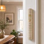Real Jerusalem stone mezuzah with cream rounded body, diamond carving, and gold-tone Shin, mounted on a doorpost in a home entrance.