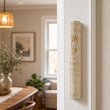 Real Jerusalem stone mezuzah with cream rounded body, diamond carving, and gold-tone Shin, mounted on a doorpost in a home entrance.