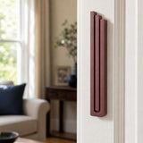 Realistic image of the exact modern burgundy pyramid mezuzah mounted vertically on a doorpost in a residential entryway, showing precise design and scale.