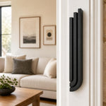 Indoor scene showing a residential door with the Midnight Black Cascade Mezuzah mounted vertically on the right doorpost, viewed from inside the room.