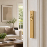 Eternal Flame Gold Aluminum Mezuzah mounted vertically on a residential doorpost, positioned within the lower third, showing its gold finish and Hebrew emblem.