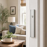 Photograph of a residential doorpost with the matte silver aluminum mezuzah mounted vertically on the right side in a home entryway.