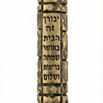 High-resolution brass Jerusalem Mezuzah with detailed Hebrew engravings and decorative motifs, on a white studio background with soft reflection.