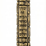 High-resolution brass Jerusalem Mezuzah with detailed Hebrew engravings and decorative motifs, on a white studio background with soft reflection.