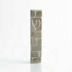 Handcrafted Jerusalem stone mezuzah in gray with detailed Hebrew engravings, displayed on a clean, white studio background with soft reflection.