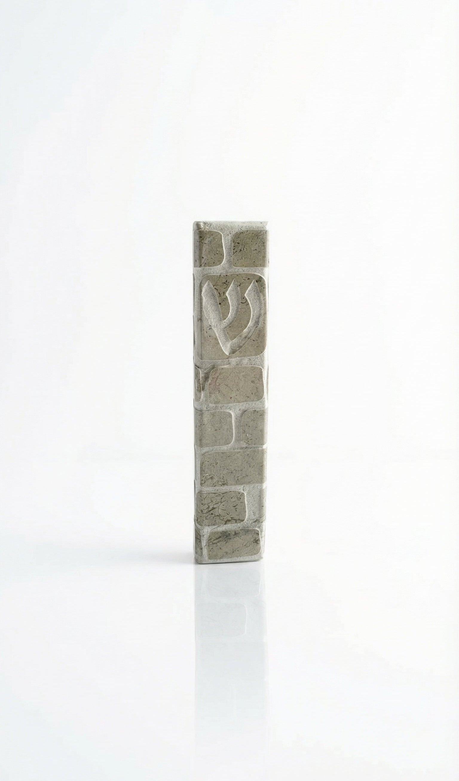 Handcrafted Jerusalem stone mezuzah in gray with detailed Hebrew engravings, displayed on a clean, white studio background with soft reflection.