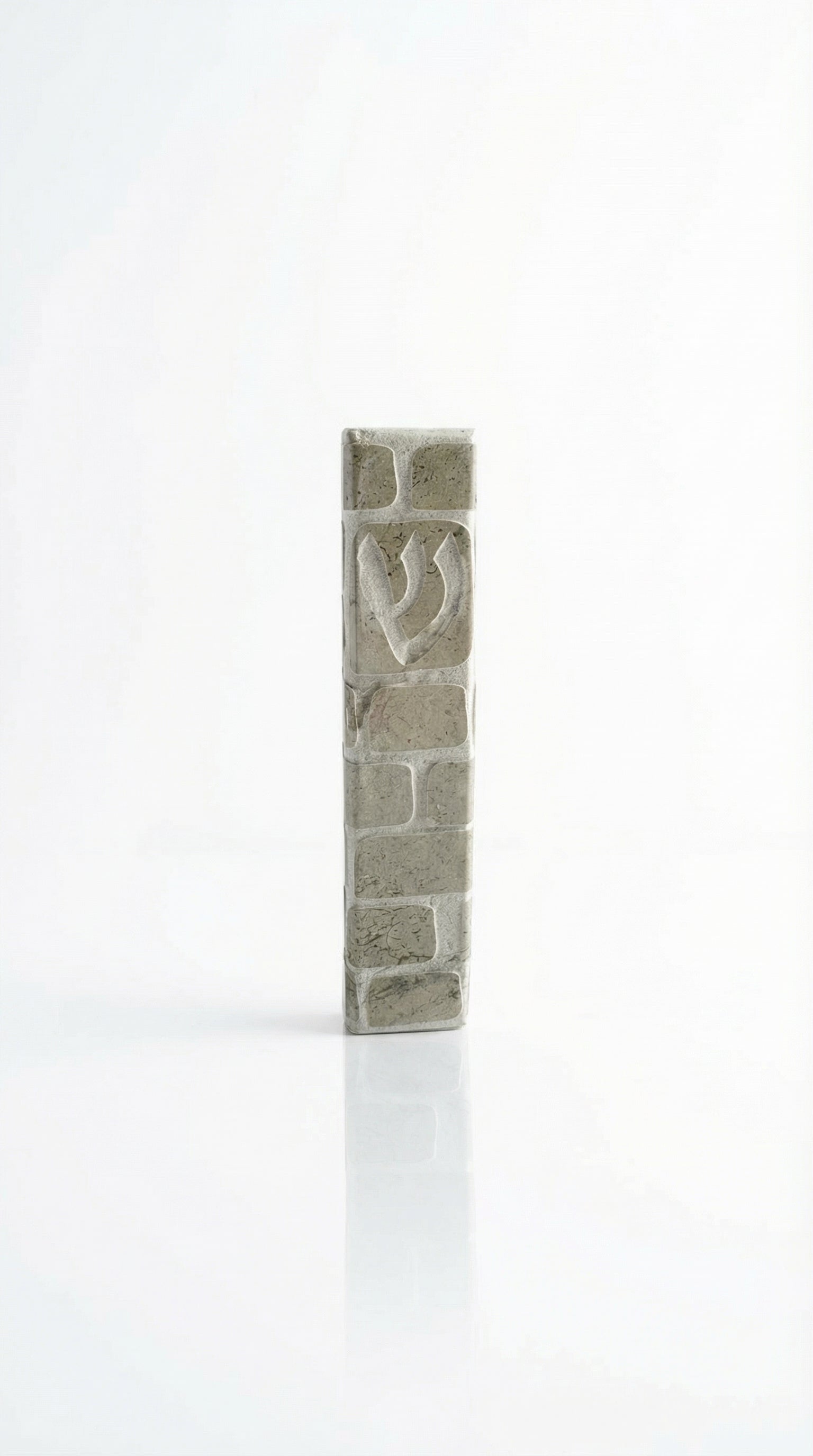 Handcrafted Jerusalem stone mezuzah in gray with detailed Hebrew engravings, displayed on a clean, white studio background with soft reflection.