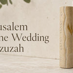 Jerusalem Stone Wedding mezuzah case displayed against a natural stone background, featuring warm cream Jerusalem stone, a flowing carved center line, Hebrew lettering along the side, and a gold Hebrew Shin on the front. A meaningful Jewish wedding, housewarming, or new home mezuzah gift with a timeless Jerusalem-inspired design