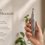 Jeweled Butterfly pewter mezuzah case held in a woman’s hand, featuring an elongated silver-tone body with two raised butterfly designs accented by clear sparkling stones and a Hebrew Shin near the top. This decorative Jewish mezuzah case fits up to a 2.8-inch kosher scroll and suits indoor or protected outdoor doorways