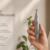 Jeweled Butterfly pewter mezuzah case held in a woman’s hand, featuring an elongated silver-tone body with two raised butterfly designs accented by clear sparkling stones and a Hebrew Shin near the top. This decorative Jewish mezuzah case fits up to a 2.8-inch kosher scroll and suits indoor or protected outdoor doorways