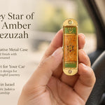 Journey Star of David Amber Car Mezuzah mezuzah cover held upright in one hand, showing an amber orange patterned face, central Star of David, green accent panels and Hebrew Shin inside a rounded gold-colored metal frame beside the product name and illustrated design features in a wide social-sharing graphic for decorative Jewish travel Judaica