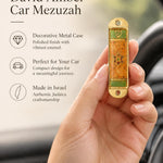 Hand holding the Journey Star of David Amber Car Mezuzah mezuzah cover inside a vehicle, showing an amber orange Star of David panel, muted green bands and a small Hebrew Shin within a gold-colored metal frame beside the product name and illustrated features for this decorative Jewish travel Judaica piece