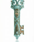 Ornate brown enamel pewter mezuzah in key shape, displayed on a white studio background with soft reflection, detailed craftsmanship.