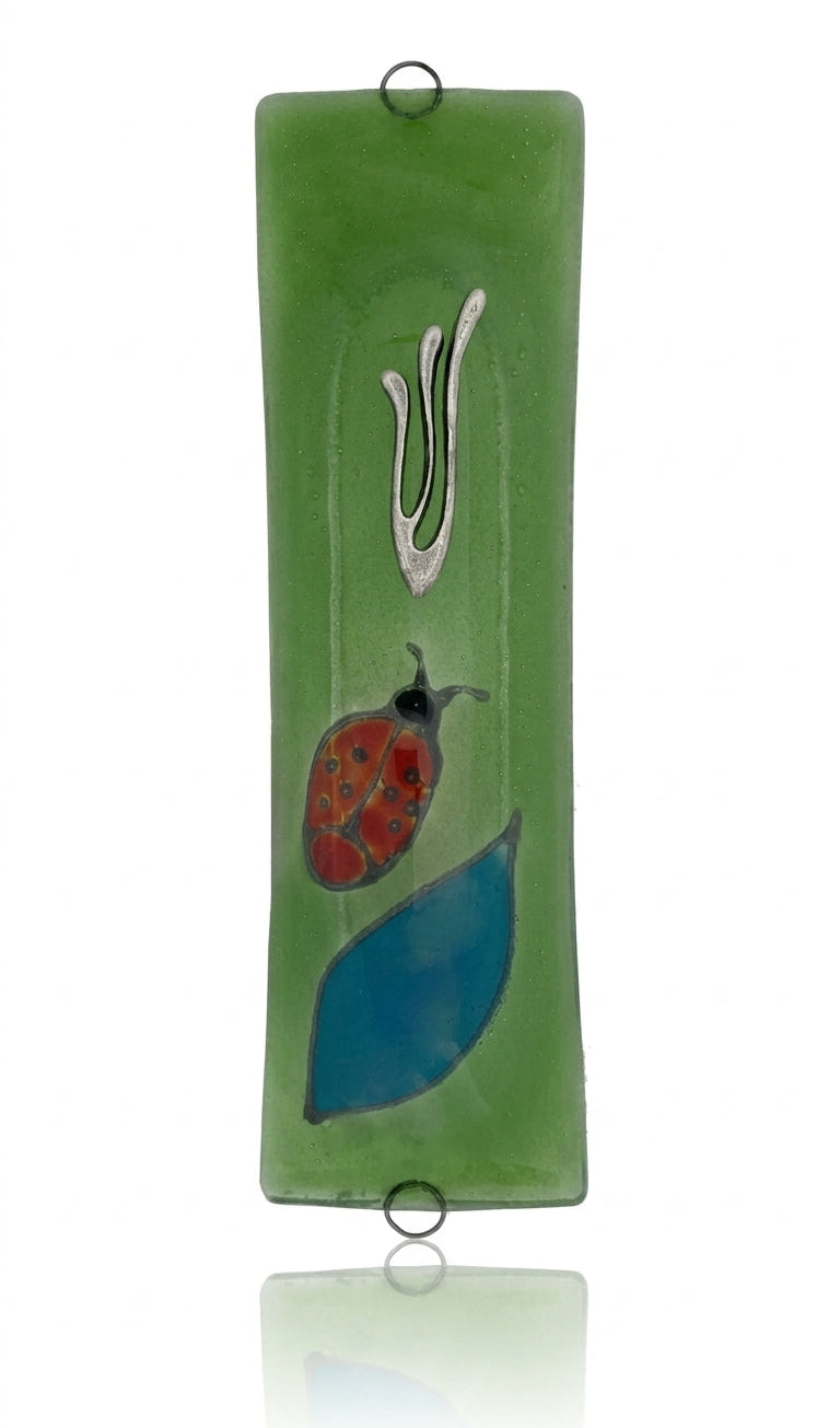 Elegant Ladybug glass mezuzah with intricate Hebrew engravings, shown on a white studio background with soft reflection.