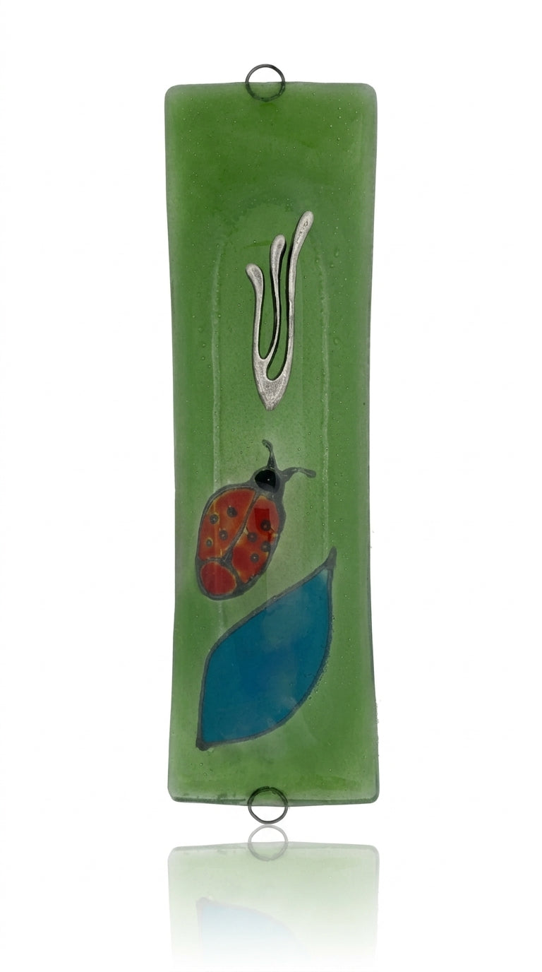 Elegant Ladybug glass mezuzah with intricate Hebrew engravings, shown on a white studio background with soft reflection.