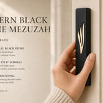 Person holding the exact black stone mezuzah with gold Shin, showcasing its size and design for outdoor or modern home entrances.