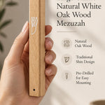 Large Classic Natural White Oak Wood Mezuzah cover held in one hand to show its long honey beige wooden body, natural grain, white outline Shin and mounting holes, with product lettering describing the traditional Hebrew design and easy mounting
