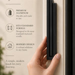 Large Modern Black Pyramid Mezuzah held beside a doorpost, with the deep matte black aluminum mezuzah cover shown close enough to reveal its three stepped bars and rounded lower edge alongside product-name and design callouts for this contemporary Judaica piece