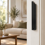 Large Modern Black Pyramid Mezuzah mounted vertically on a white interior doorpost, where its deep matte black aluminum mezuzah cover and three graduated bars create a contemporary Judaica accent with clean geometric lines against the pale doorframe