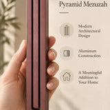 A hand presents the Large Modern Burgundy Pyramid Mezuzah with its muted burgundy wine-red aluminum mezuzah cover facing forward, highlighting the clean graduated bars and geometric vertical profile beside design illustrations for a contemporary Jewish doorway accent