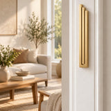 Large Modern Gold Pyramid Mezuzah mounted vertically on a white interior doorpost, where its warm metallic gold aluminum mezuzah cover and three graduated bars create a contemporary Judaica accent with clean geometric lines against the pale doorframe