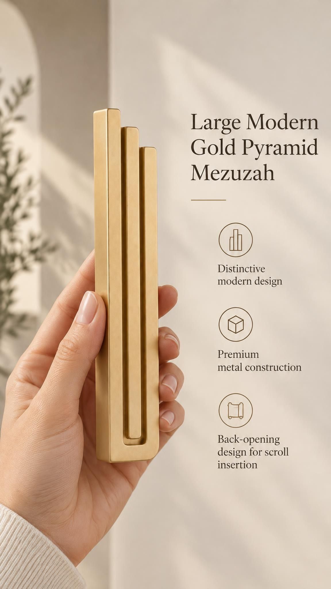 Hand holding the Large Modern Gold Pyramid Mezuzah upright, revealing its warm metallic gold aluminum mezuzah cover, slender three-bar Pyramid design and graduated top beside illustrated product features for contemporary Jewish home Judaica