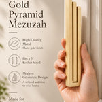 A hand presents the Large Modern Gold Pyramid Mezuzah with its warm metallic gold aluminum mezuzah cover facing forward, highlighting the clean graduated bars and geometric vertical profile beside design illustrations for a contemporary Jewish doorway accent