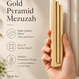 A hand presents the Large Modern Gold Pyramid Mezuzah with its warm metallic gold aluminum mezuzah cover facing forward, highlighting the clean graduated bars and geometric vertical profile beside design illustrations for a contemporary Jewish doorway accent