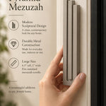 Large Modern Sandstone Pyramid Mezuzah held beside a doorpost, with the warm taupe sandstone aluminum mezuzah cover shown close enough to reveal its three stepped bars and rounded lower edge alongside product-name and design callouts for this contemporary Judaica piece