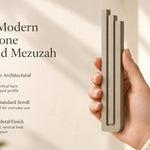 Large Modern Sandstone Pyramid Mezuzah pictured in hand as a warm taupe sandstone aluminum mezuzah cover with three graduated bars and a contemporary stepped design, alongside its name and illustrated product features in a wide social-sharing image