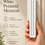 A hand presents the Large Modern White Pyramid Mezuzah with its smooth matte white aluminum mezuzah cover facing forward, highlighting the clean graduated bars and geometric vertical profile beside design illustrations for a minimalist Jewish doorway accent