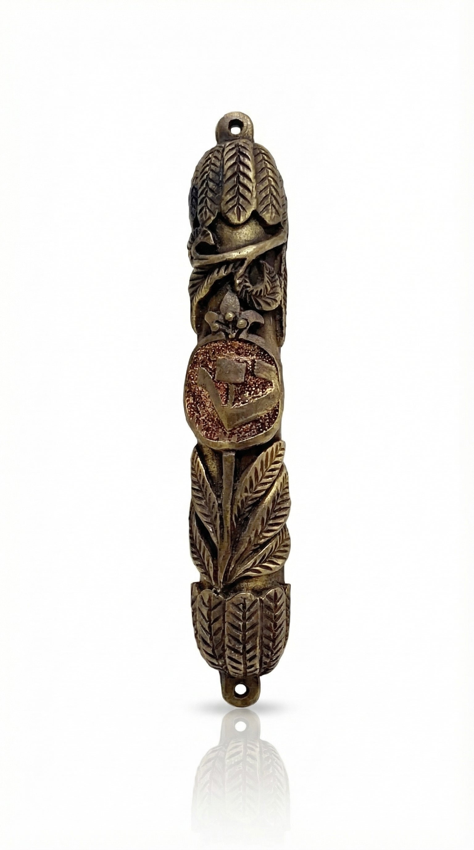 Elevated image of a brass Leafs Mezuzah with detailed engravings, Hebrew lettering, and a polished finish, mounted on a white studio backdrop.