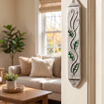 Leaves mezuzah case featuring green enamel leaves and silver pewter mounted vertically on a residential doorway.