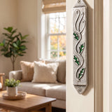 Leaves mezuzah case featuring green enamel leaves and silver pewter mounted vertically on a residential doorway.