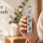 Person holding a green enamel and silver pewter leaf-themed mezuzah case, showcasing its compact size and botanical design
