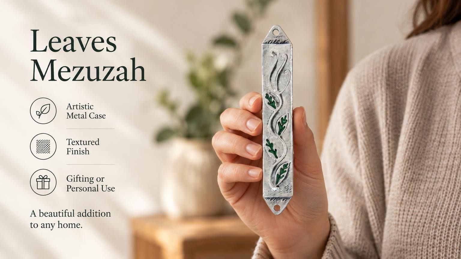 Person holding a green enamel and silver pewter leaf-themed mezuzah case, showcasing its compact size and botanical design