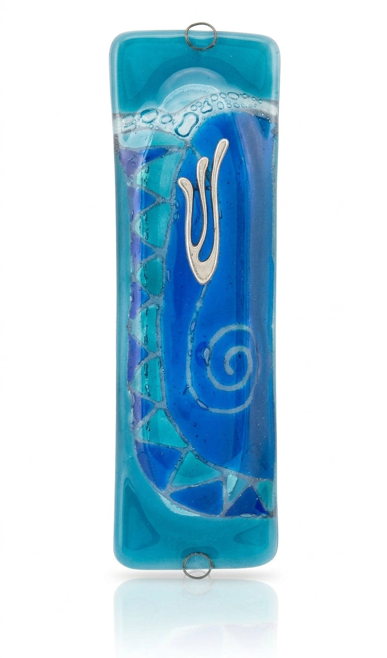 Elegant light blue glass mezuzah measuring 4.5 inches tall with engraved Hebrew letters and decorative motifs, mounted on a white background with subtle reflection.