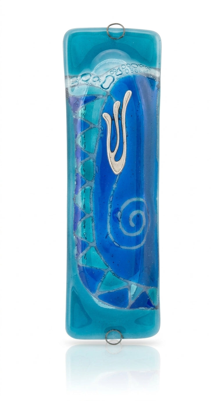 Elegant light blue glass mezuzah measuring 4.5 inches tall with engraved Hebrew letters and decorative motifs, mounted on a white background with subtle reflection.
