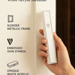 Person holding a slim white acrylic mezuzah case with a silver frame and Shin letter against a clean editorial background.