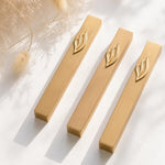 Premium gold mezuzah case with silver accents and minimalist rectangular design, displayed on a clean white surface with pampas flowers