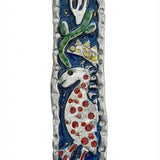 Upscale image of a Marc Chagall style Mezuzah with intricate Hebrew engravings, detailed motifs, on a bright white studio surface with light reflection.