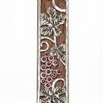 Mahogany Mezuzah with curling pewter vine and maroon stones depicting the holy land, shown on a white background with soft reflection.