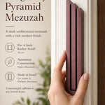 Individual holding the exact modern burgundy pyramid mezuzah at realistic scale, with space for editorial text, emphasizing its precise dimensions and design features.