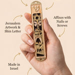 Minimalist callout of a person holding Jerusalem’s Golden Gates mezuzah, highlighting the intricate Jerusalem artwork and enamel finish.