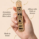 Minimalist callout of a person holding Jerusalem’s Golden Gates mezuzah, highlighting the intricate Jerusalem artwork and enamel finish.