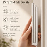 Elegant display of a person presenting the modern silver pyramid mezuzah, emphasizing its clean architectural style.