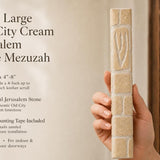 Close-up of cream Jerusalem stone mezuzah in hand with neutral background, highlighting material and finish.