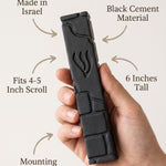 Close-up of a person gently holding a black cement mezuzah, emphasizing its size, material, and design details in a clean, minimalist layout.