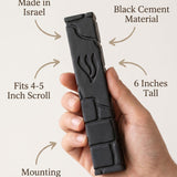 Close-up of a person gently holding a black cement mezuzah, emphasizing its size, material, and design details in a clean, minimalist layout.