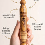 Person holding olive wood mezuzah, emphasizing craftsmanship and material details in a clean layout.